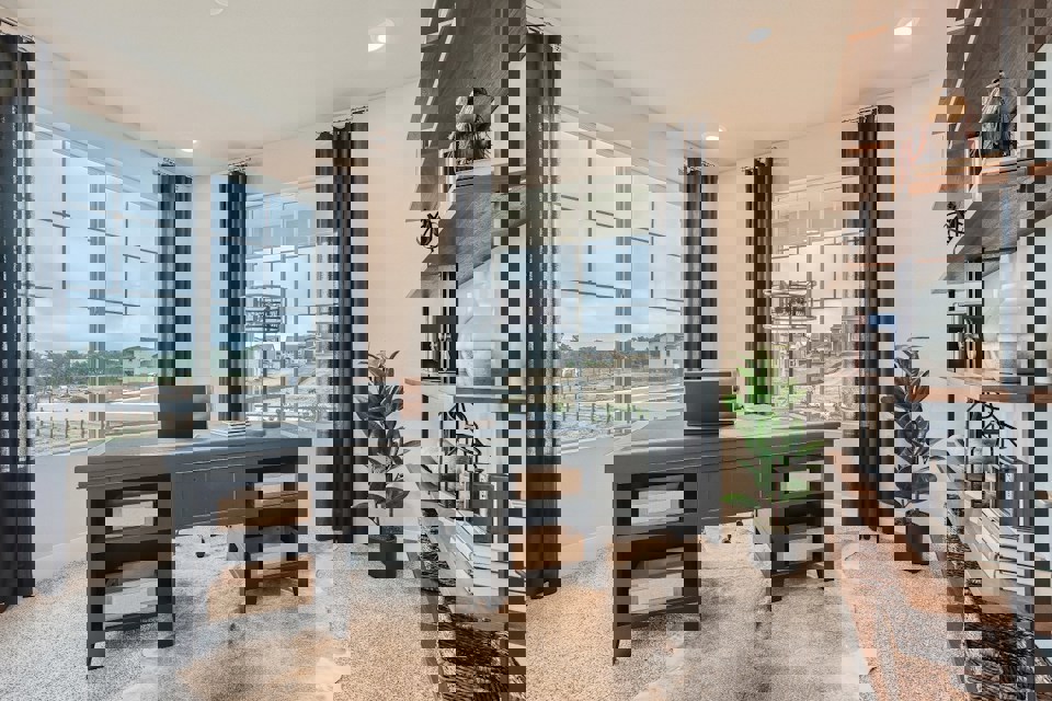 A room with a desk and a window with a view of a city.