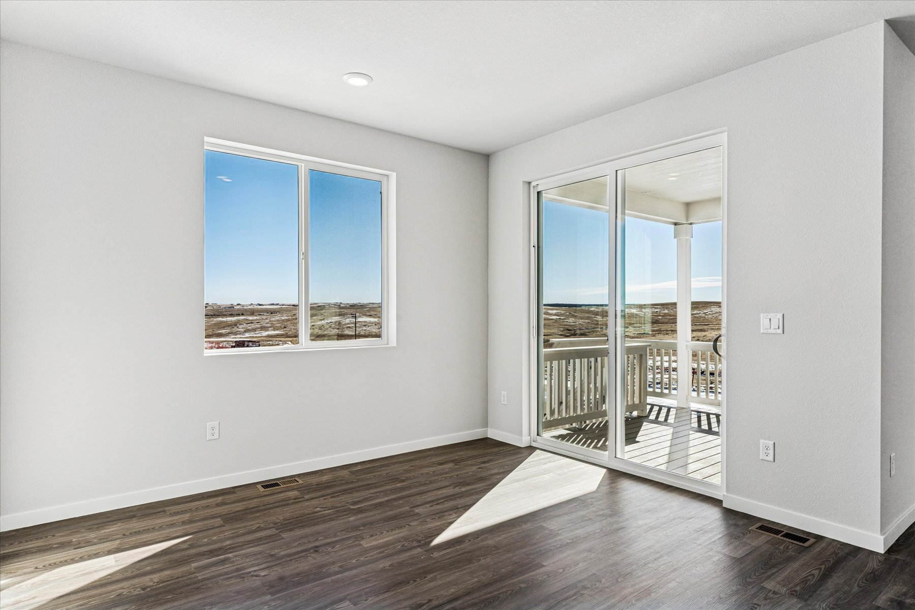 A room with a glass door and a wood floor with a wood floor.