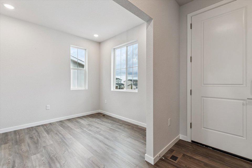 A room with white walls and a wood floor with a window.