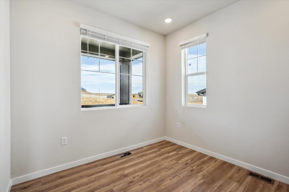 A room with a wood floor and a window with a view of the ocean.