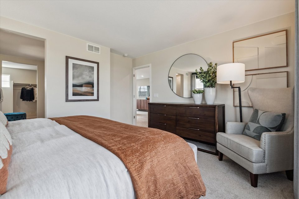 A bedroom with a bed and a chair.