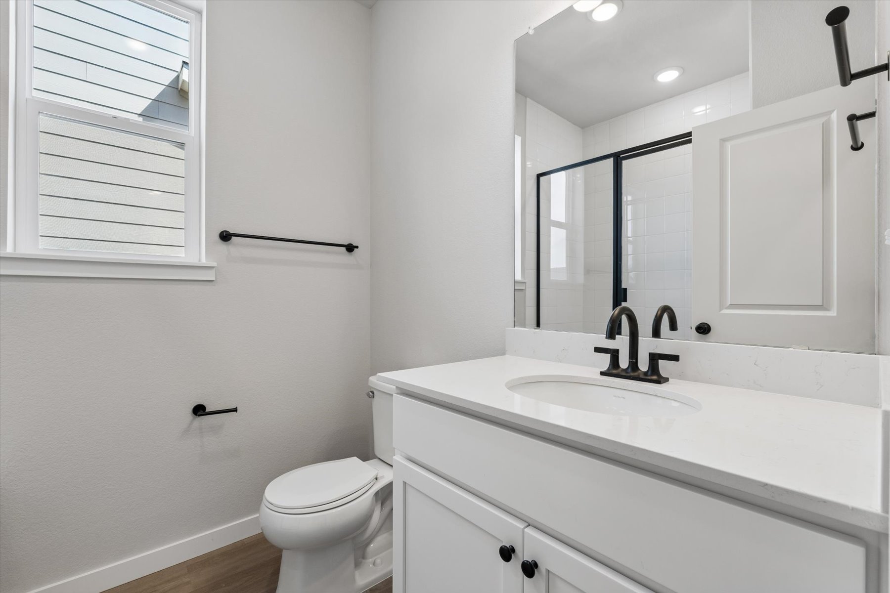 A bathroom with a sink toilet and mirror.