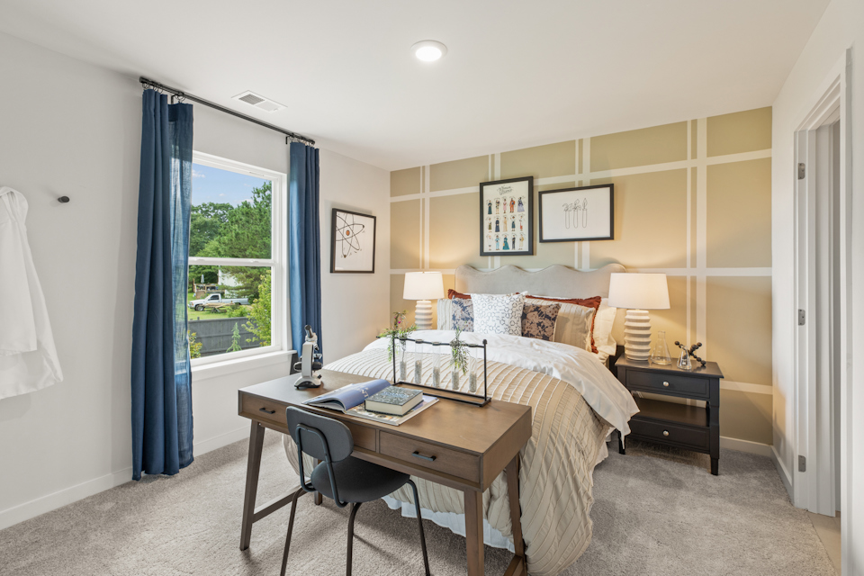 A bedroom with a bed desk and a window.