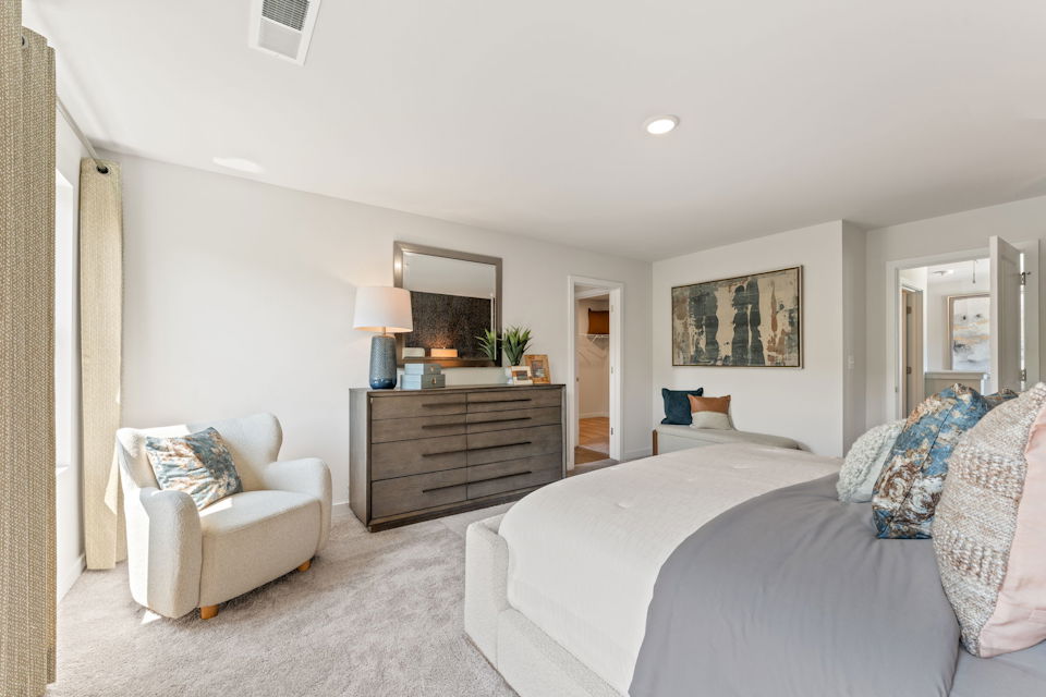 A bedroom with a bed and a chair.