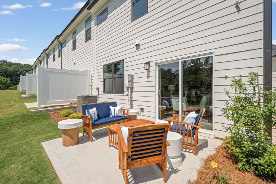 A patio with chairs and a table outside of a house.