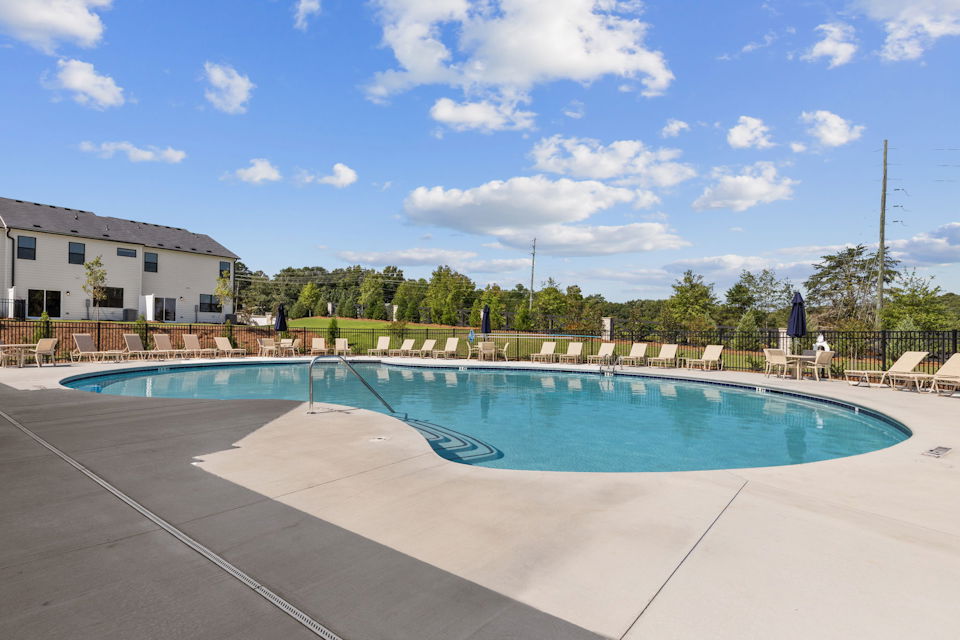 A swimming pool with a fence and trees in the background.