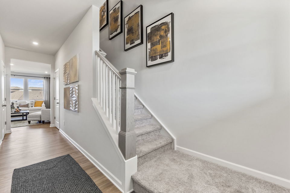 A white staircase with pictures on the wall.