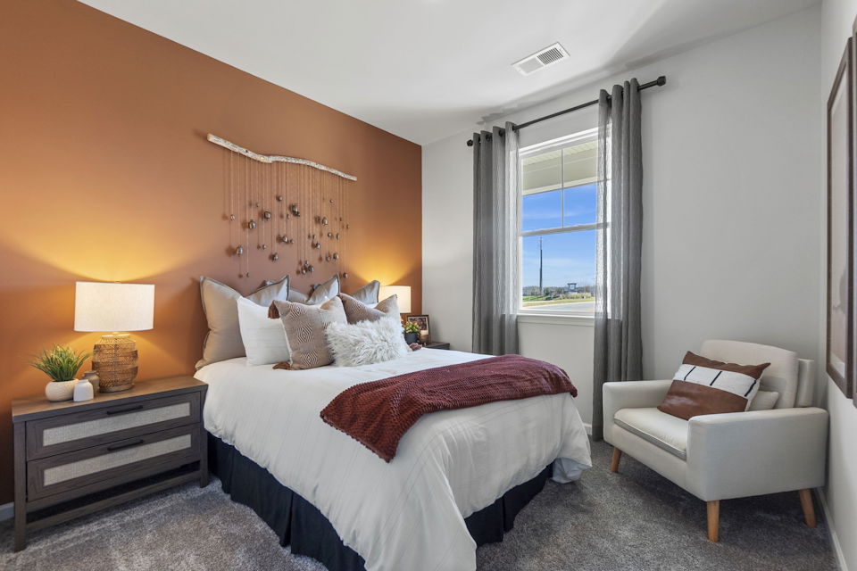 A bedroom with a bed and a chair.