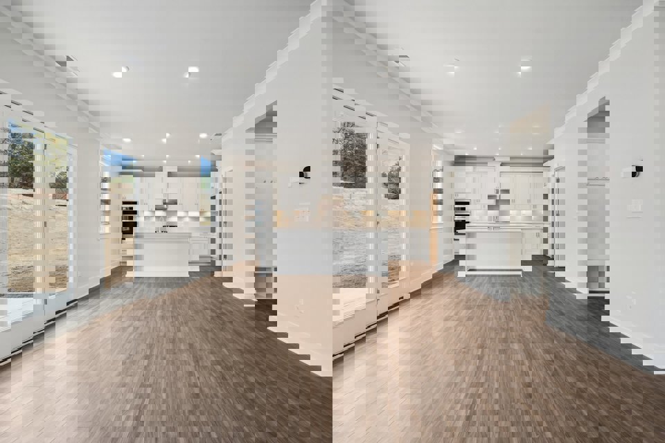 A large white kitchen with a wood floor.