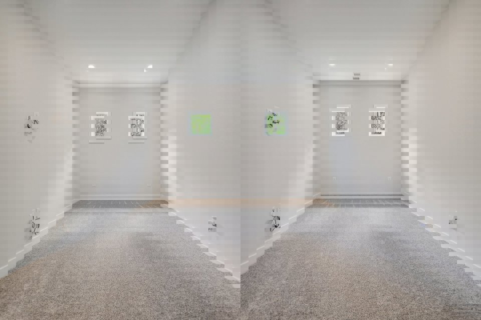 A room with a carpet and a white wall with pictures on it.