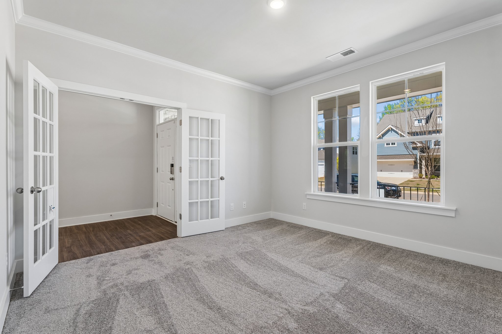 A room with white walls and a window with a view of a boat.