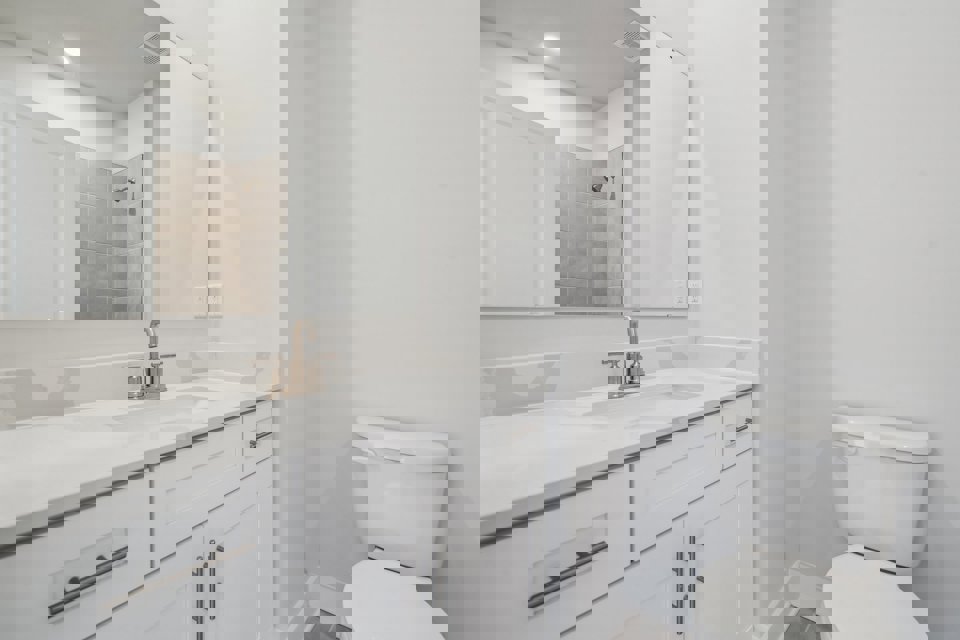 A bathroom with a sink toilet and mirror.