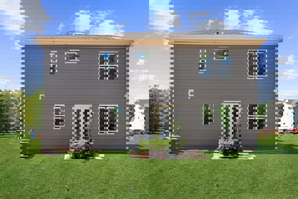 A house with a grass yard with James K. Polk Ancestral Home in the background.