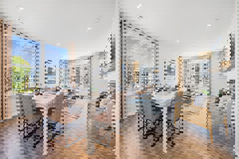 A large living room with a large dining table and a large window.