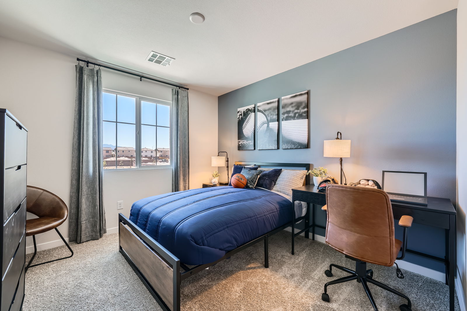 A bedroom with a bed desk and a chair.