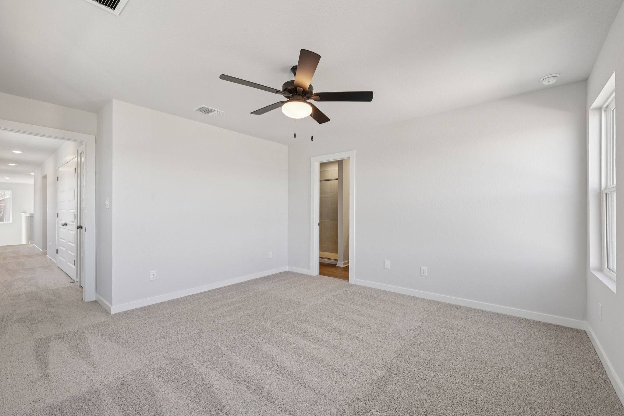 A room with a ceiling fan and a door.