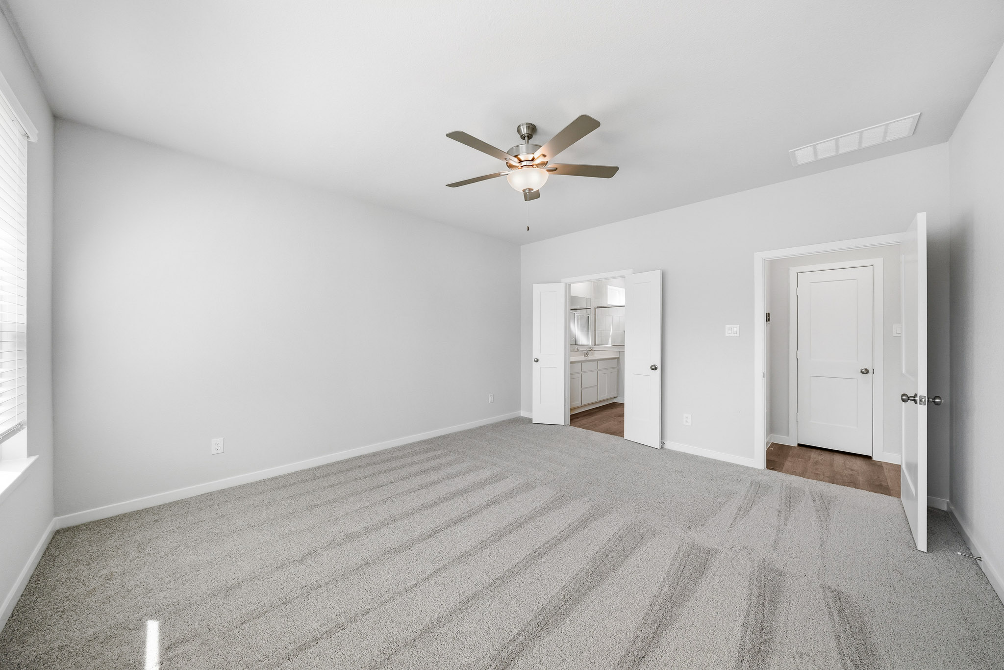 A room with a ceiling fan and a carpet.