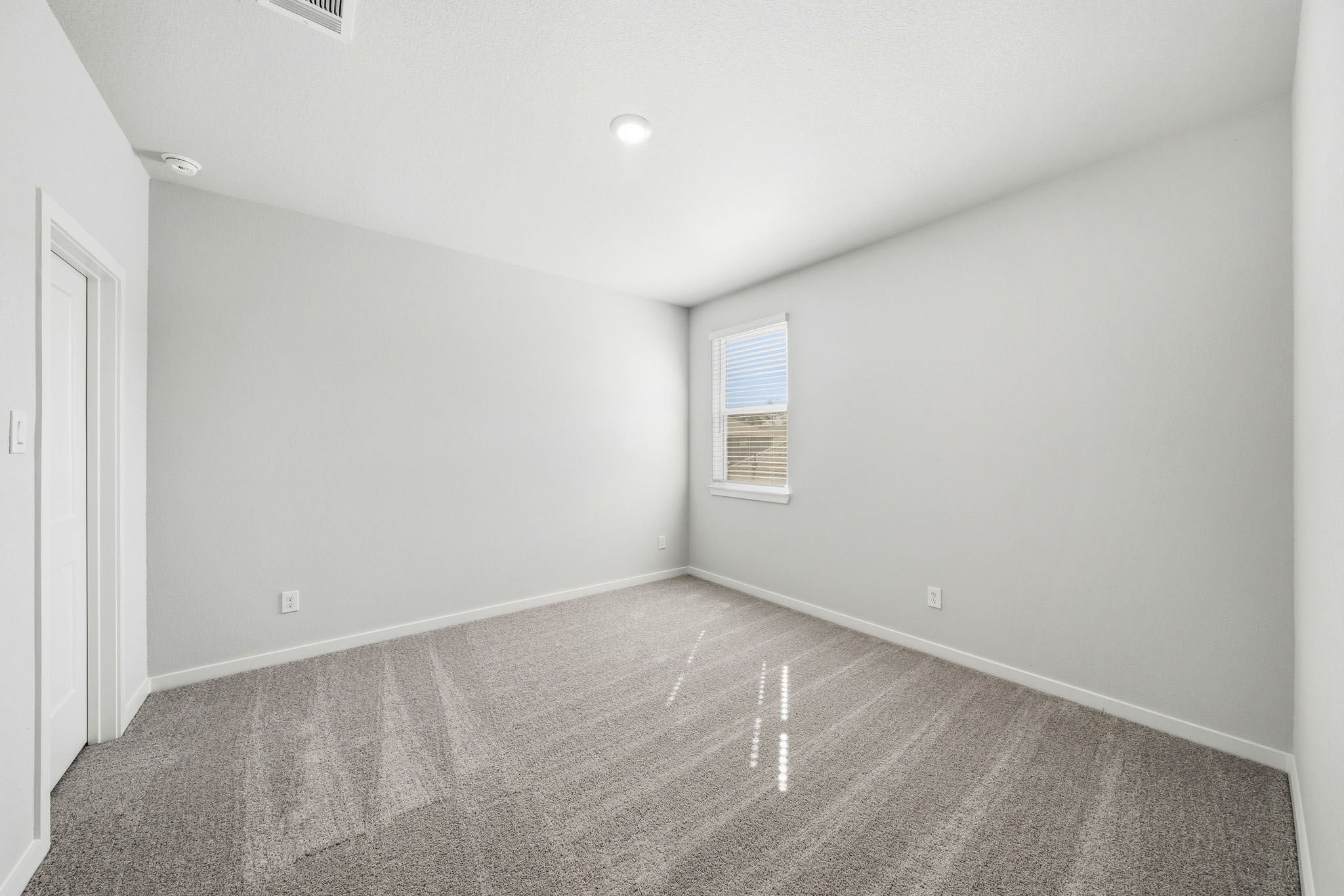 A room with a carpet and a window.