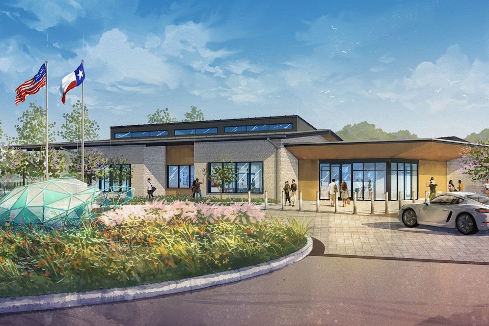 A building with a large flower bed and a car parked in front.