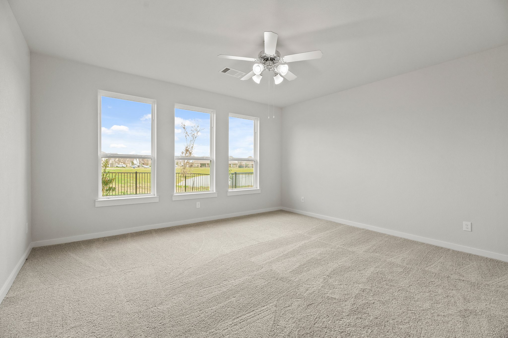 A room with a ceiling fan and a window with a view of the ocean.