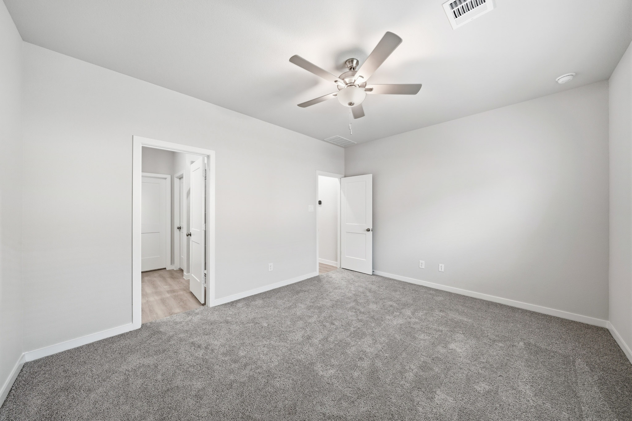 A room with a ceiling fan and a door.