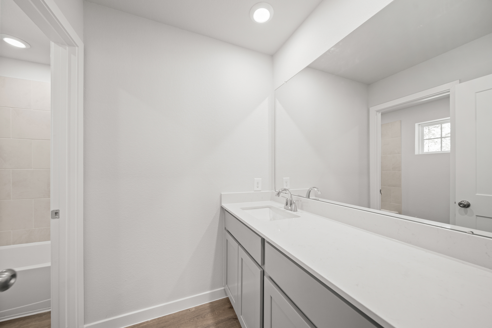 A bathroom with a tub sink and a mirror.