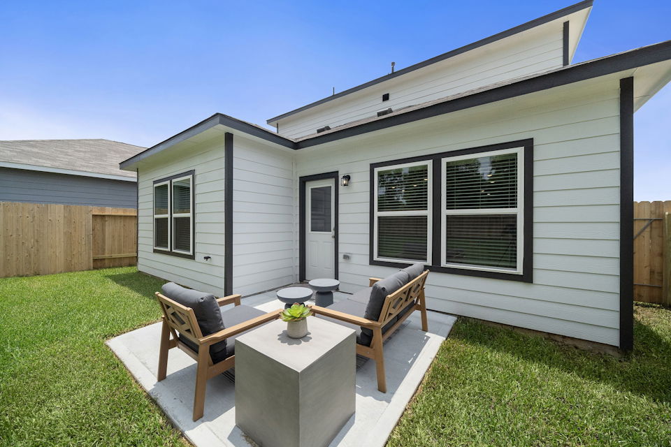 A backyard with a bench and a table and chairs.