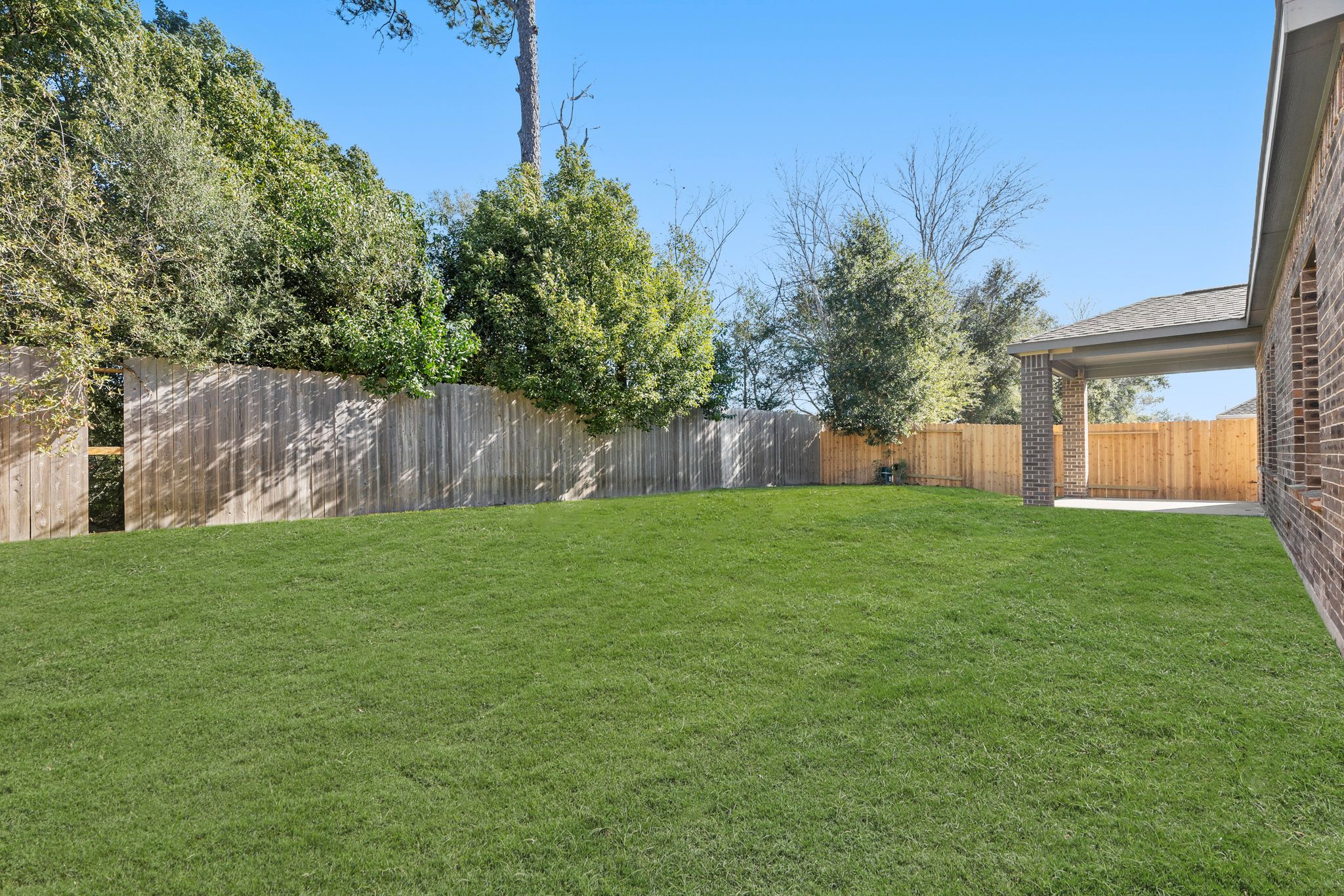 A fenced in yard with trees and a building in the background.