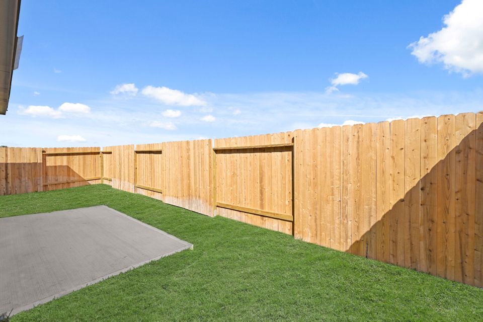 A fenced in area with a walkway and grass.