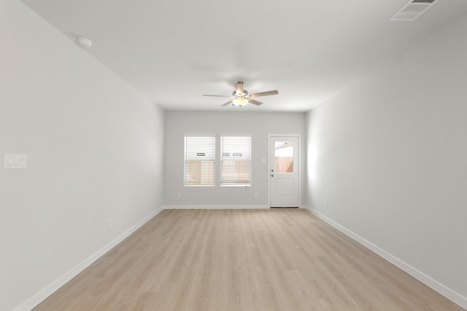 A room with a ceiling fan and a wood floor.