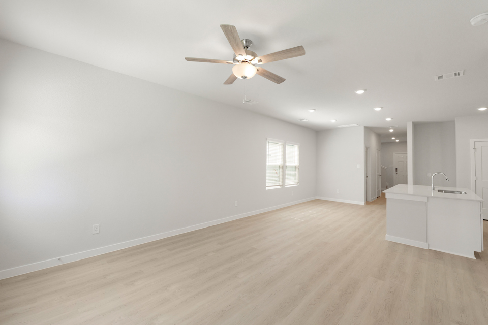 A large empty room with a ceiling fan and a wood floor.