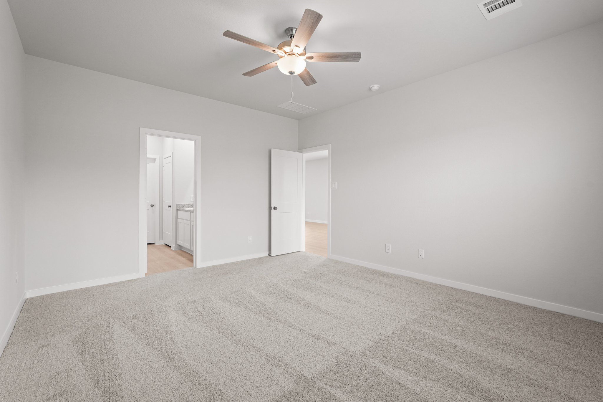 A room with a ceiling fan and a carpet.