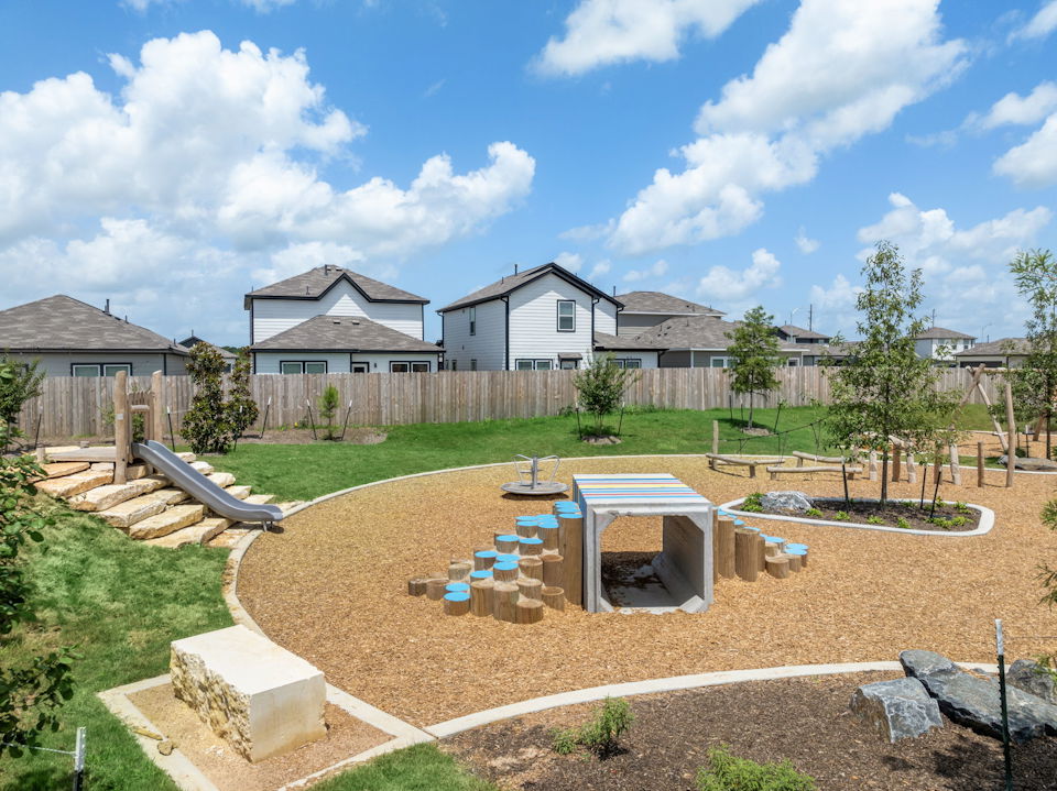 A backyard with a fence and a yard with a house in the background.