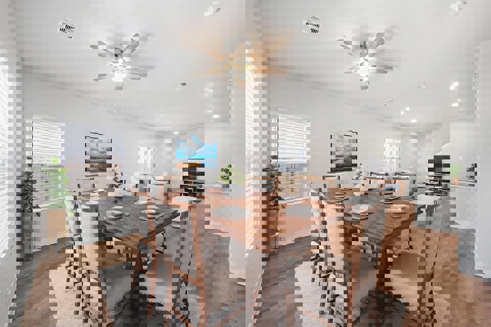 A dining room table with plates and a fan in the background.