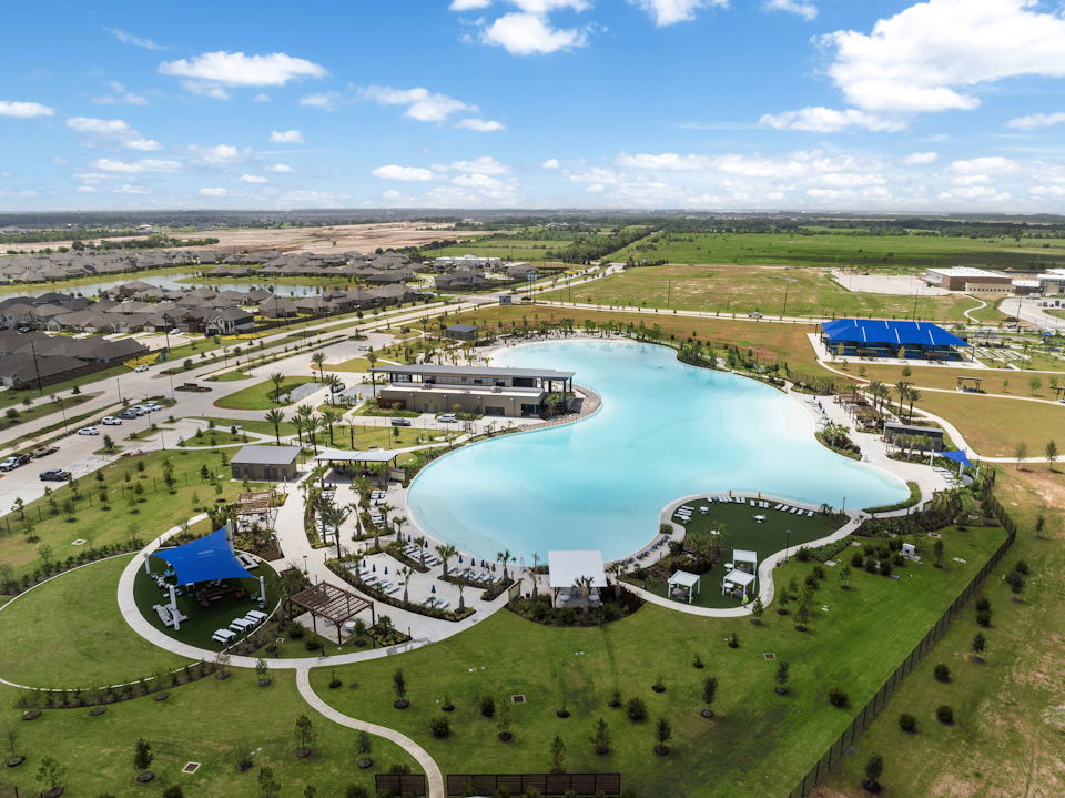 A large body of water surrounded by grass and buildings.