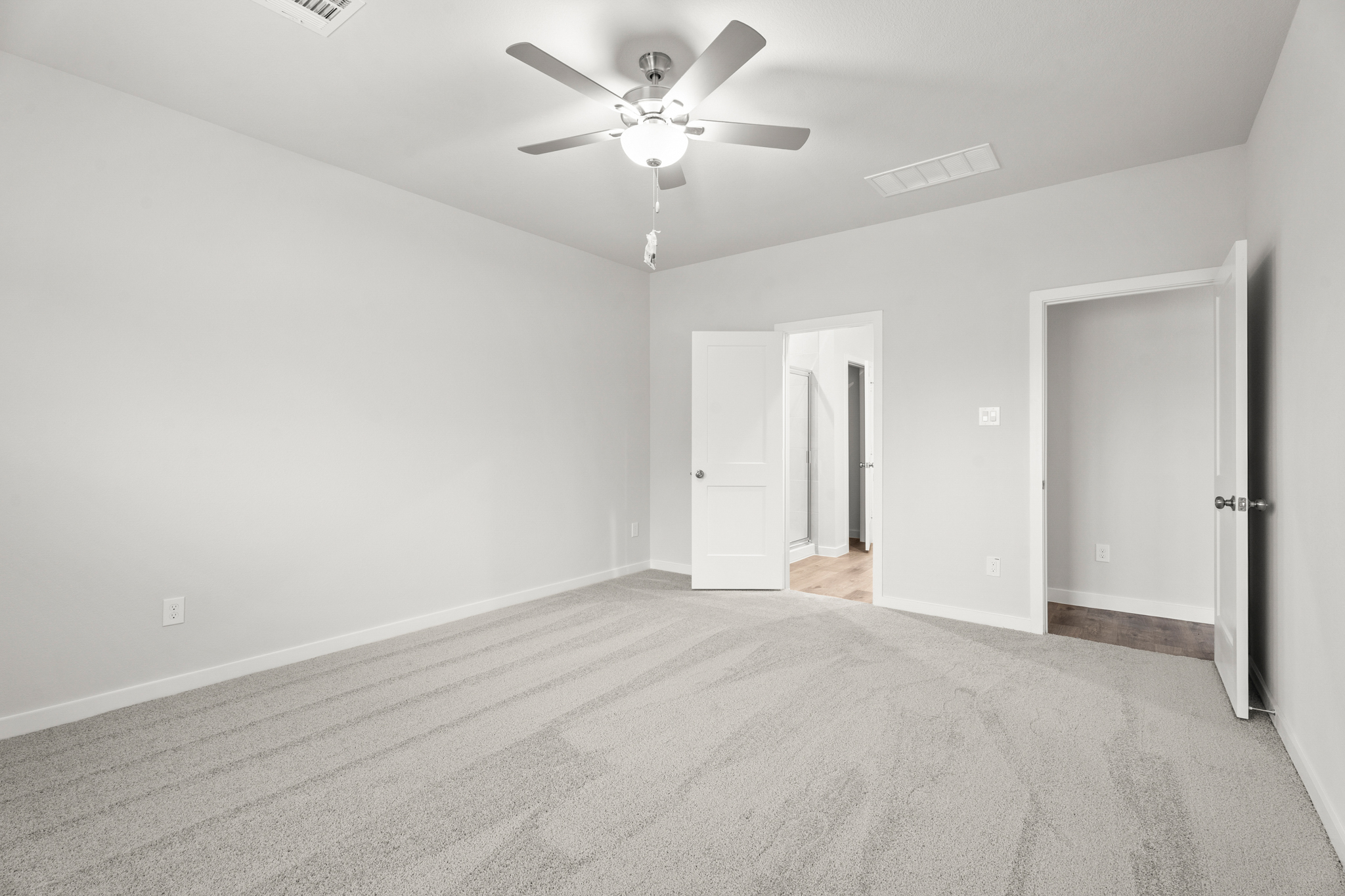A room with a ceiling fan and a door.