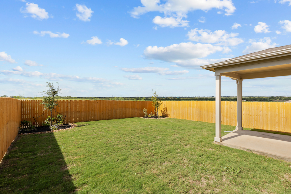 A fenced in yard with a wood building and a wood fence.