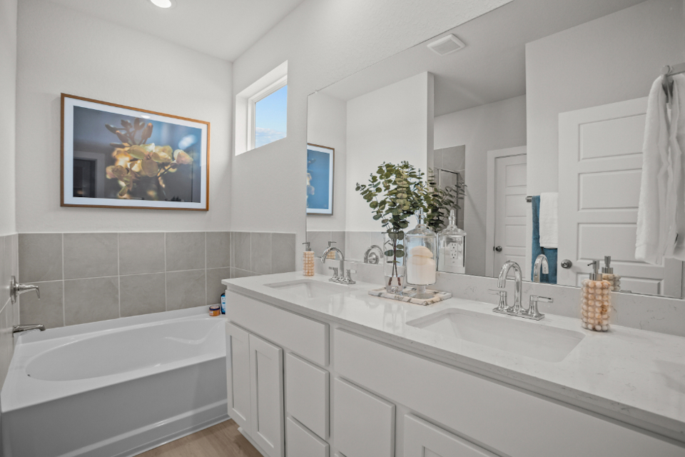 A bathroom with a tub sink and a mirror.