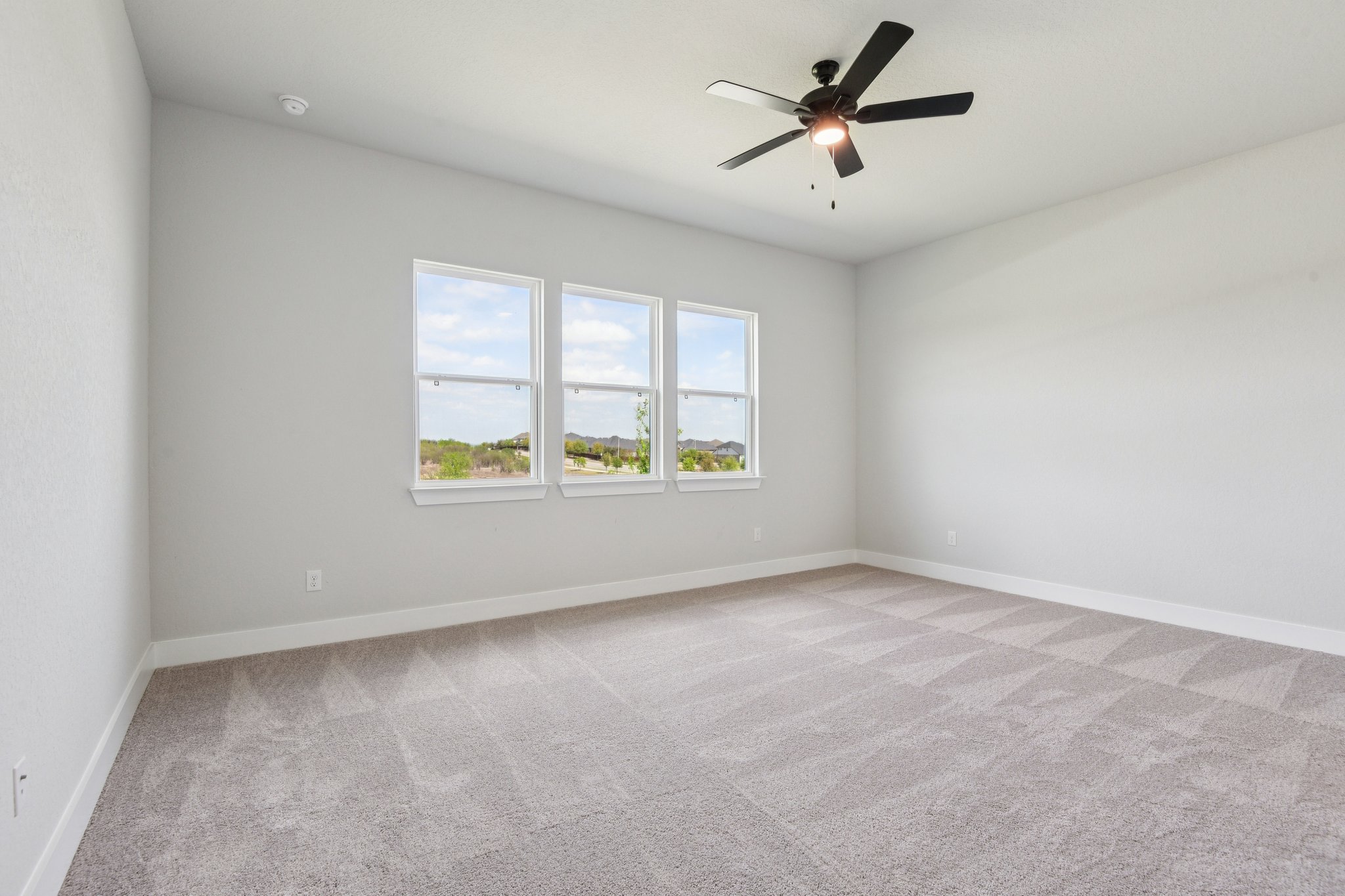 A room with a ceiling fan and a window with a light.