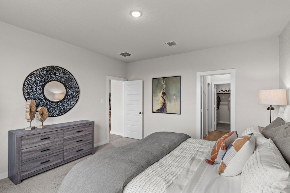 A bedroom with a bed and a mirror.