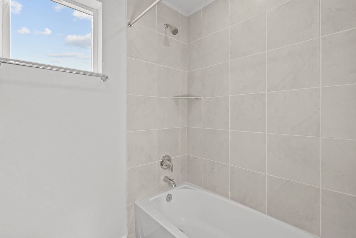 A bathroom with a bathtub and window.