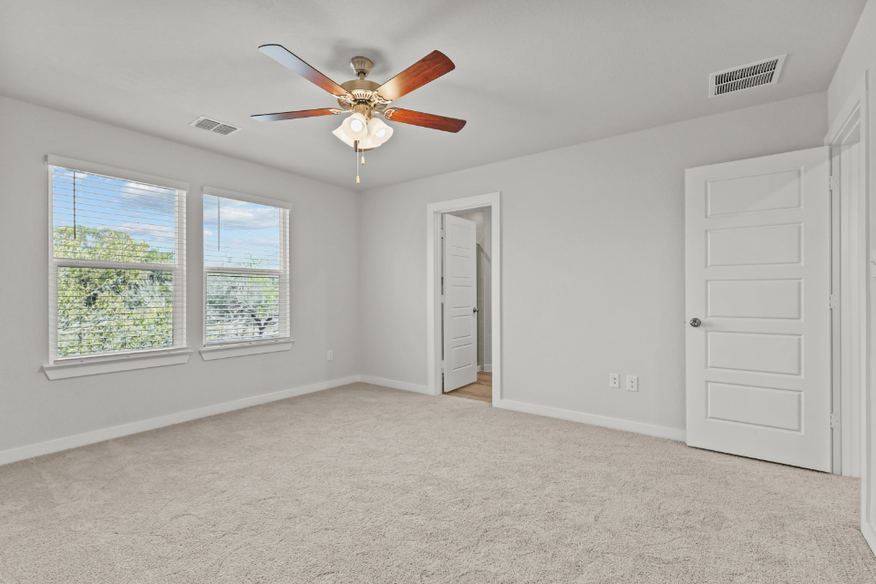 A room with a ceiling fan and a door.