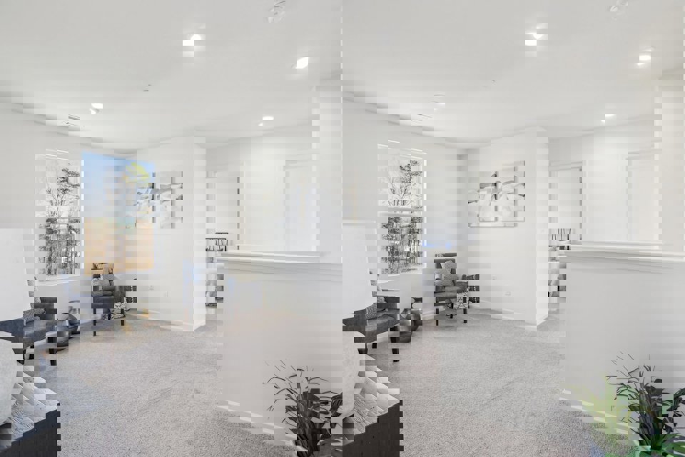 A room with a couch and chairs.