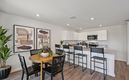 A kitchen with a dining table and chairs.