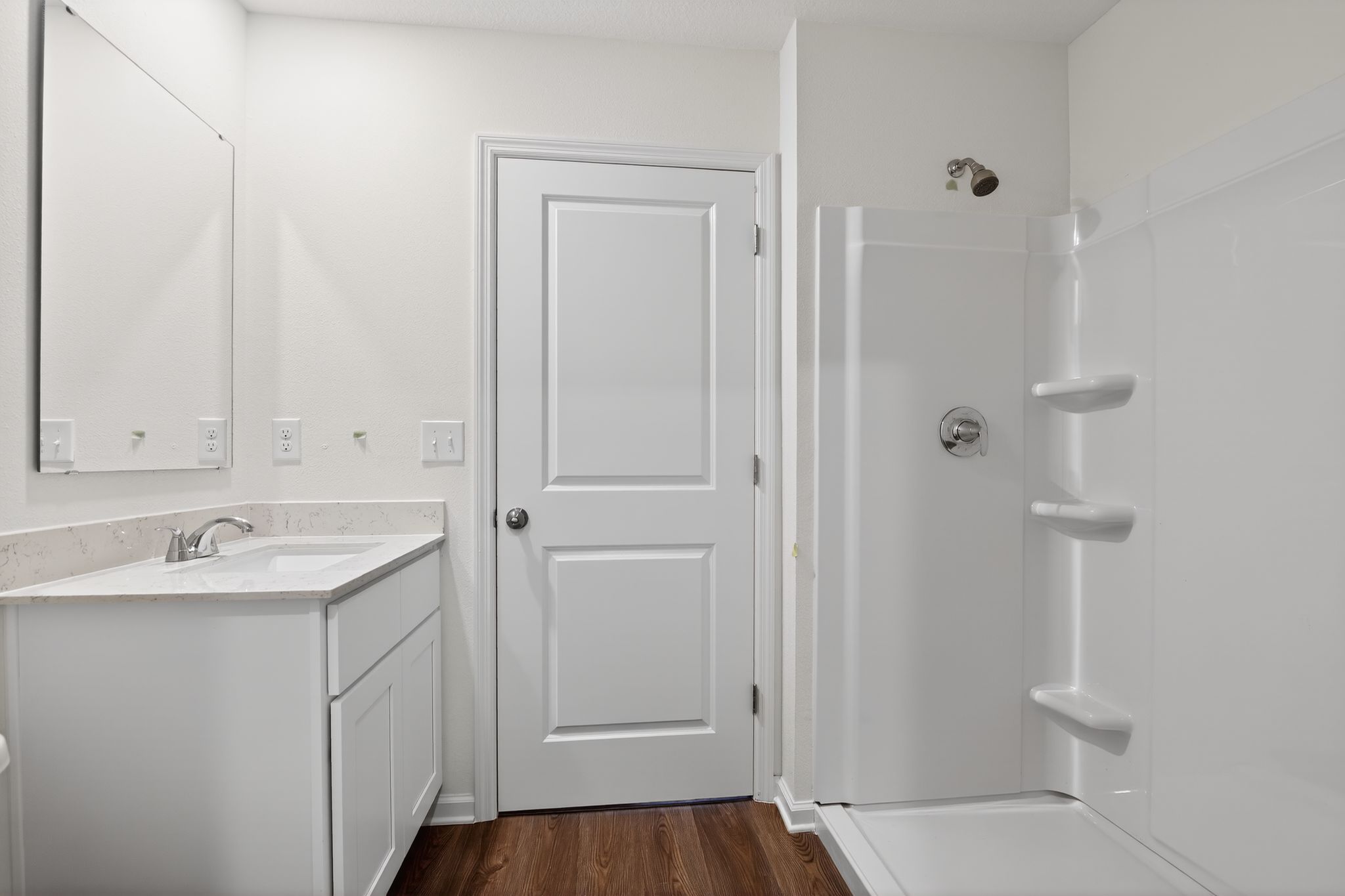 A bathroom with a sink and a shower unit.
