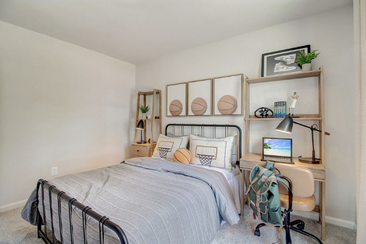 A bedroom with a bed desk and a laptop.